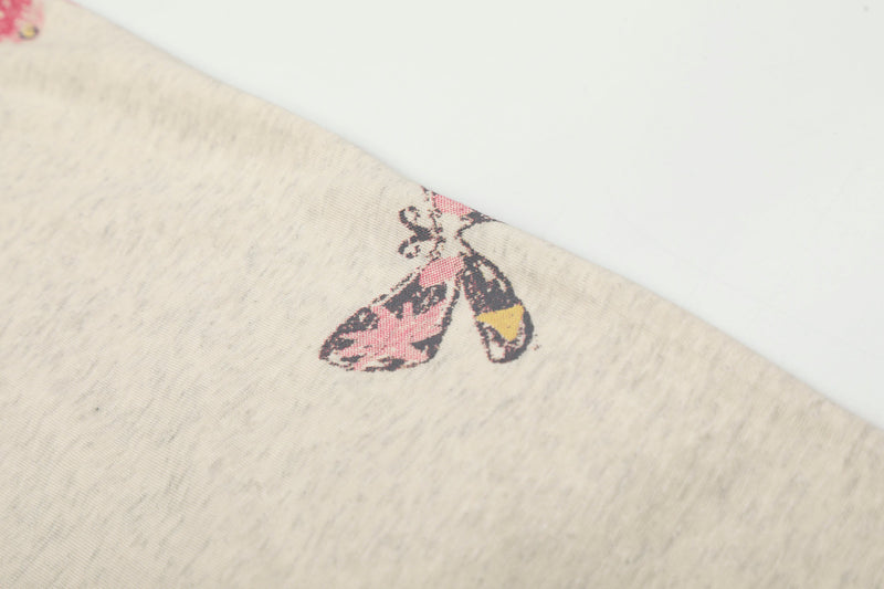Close-up of small butterfly print on cream tee sleeve