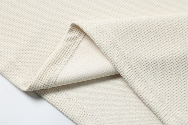 Close-up of sleeve cuff and inner seam on cream textured fabric