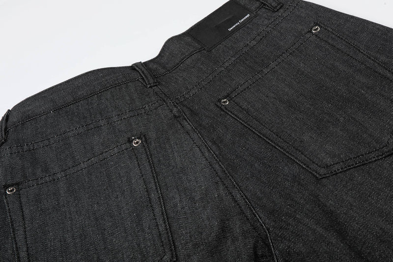 Close-up of back waistband and patch pocket on black denim shorts with logo label