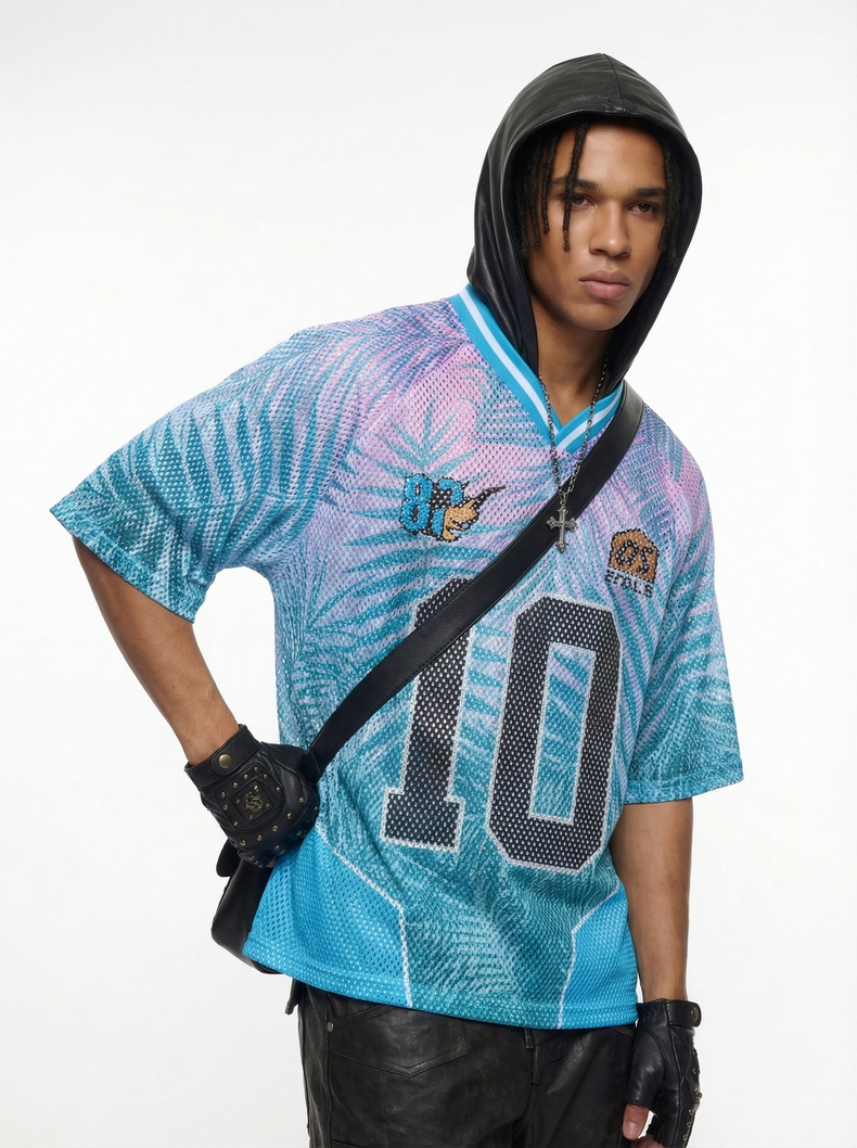 Model wearing a blue and pink mesh jersey T-shirt with large number 10, black hood, gloves, and cross necklace