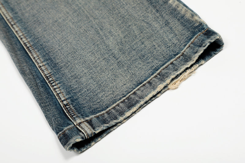 Close-up of a frayed hem on faded blue wide-leg denim jeans