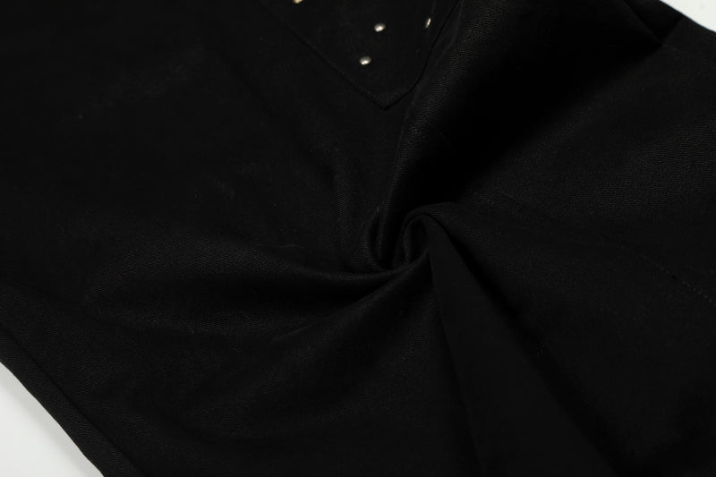 Close-up of black pants fabric folds and top snap studs