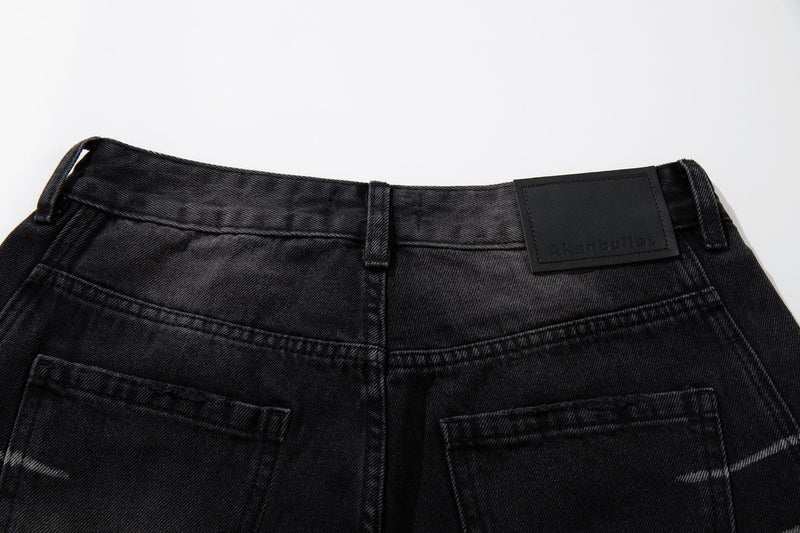 Close-up of the back waistband on washed black jeans with a black logo patch and belt loops