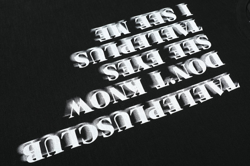 Close-up of black tee front graphic with tilted white vertical slogan print