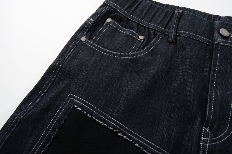 Close-up of the front left pocket on dark denim jeans with metal rivets and topstitching