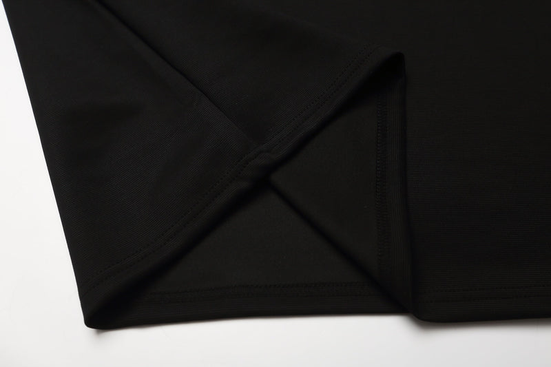 Close-up of a black cotton gothic polo shirt with stitched hem and textured fabric detail