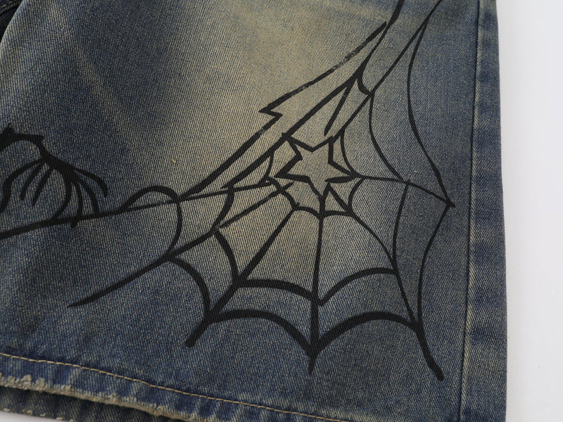 Close-up of spider web and spider graphic on the leg of blue denim shorts