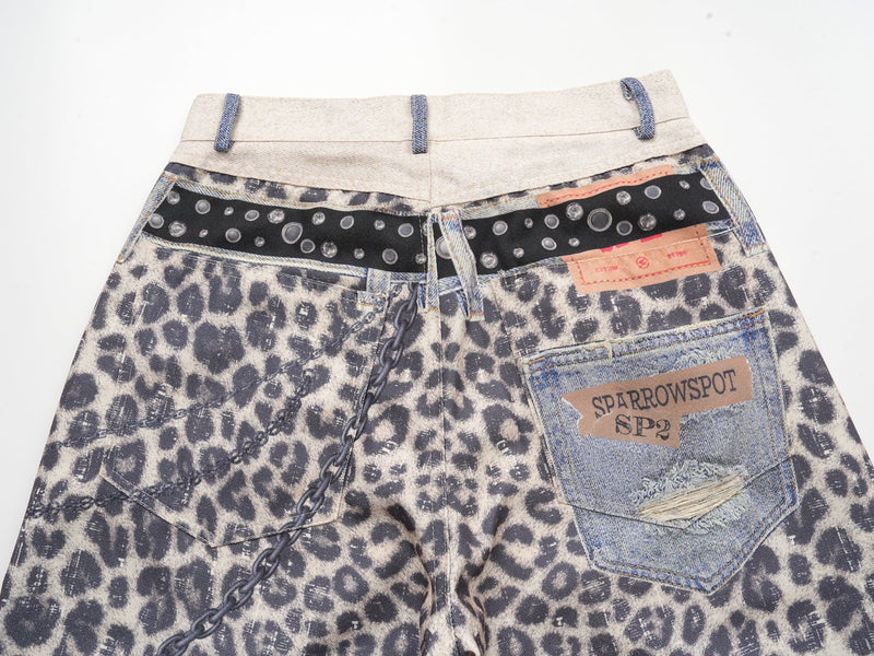 Back waistband close-up with leopard print fabric, black studded belt strip, and denim patch pocket