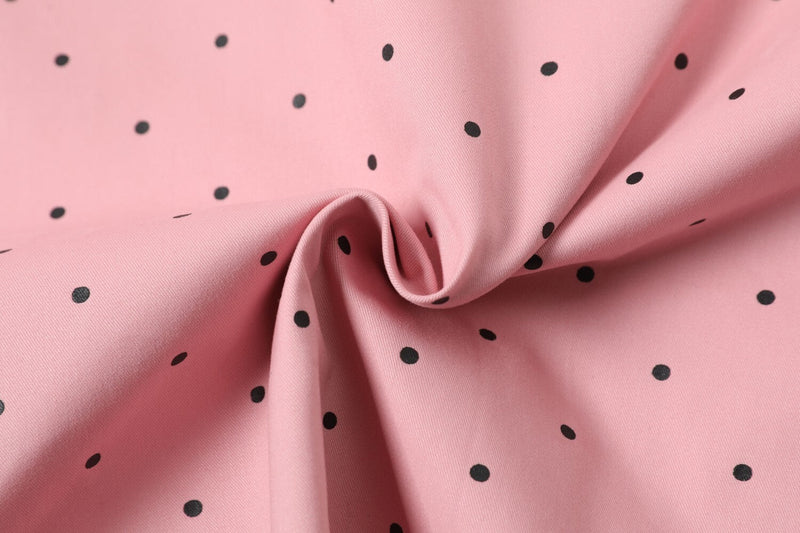 Close-up of pink fabric with black polka dots and gathered folds