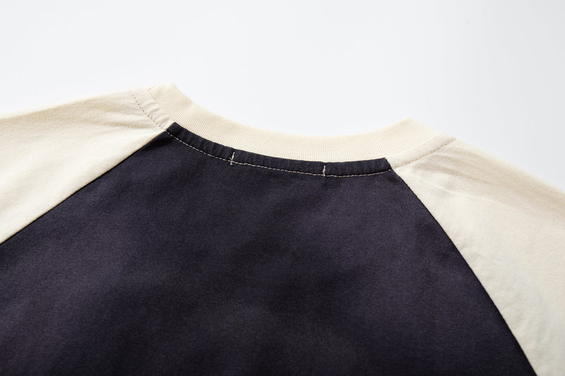 Close-up of a vintage raglan tee with cream sleeves, black body, and a ribbed crew neckline