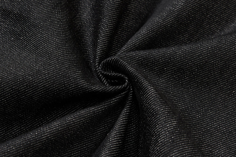 Close-up of black denim fabric texture with soft folds and white flecks