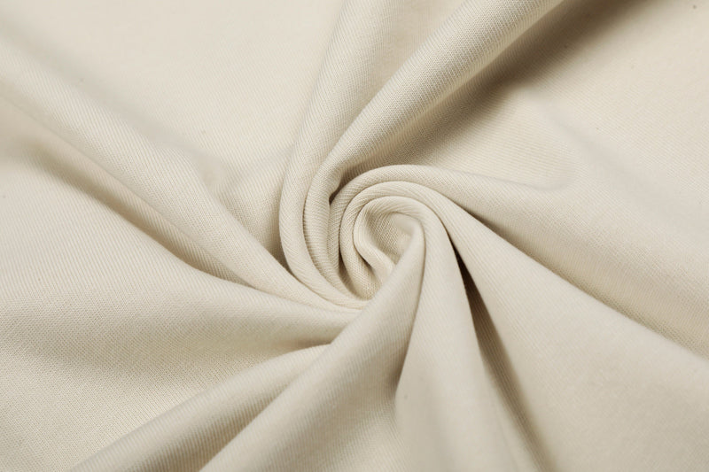 Close-up of cream cotton tee fabric with soft folds, showing the oversized Blackenergy Star Script graphic shirt material and texture