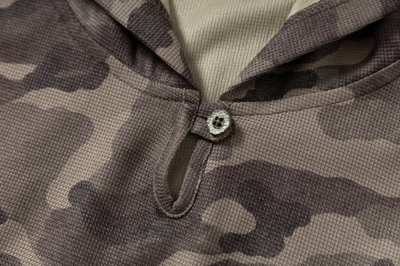 Close-up of a camo hooded short-sleeve tee with textured fabric, button detail, and oversized streetwear style