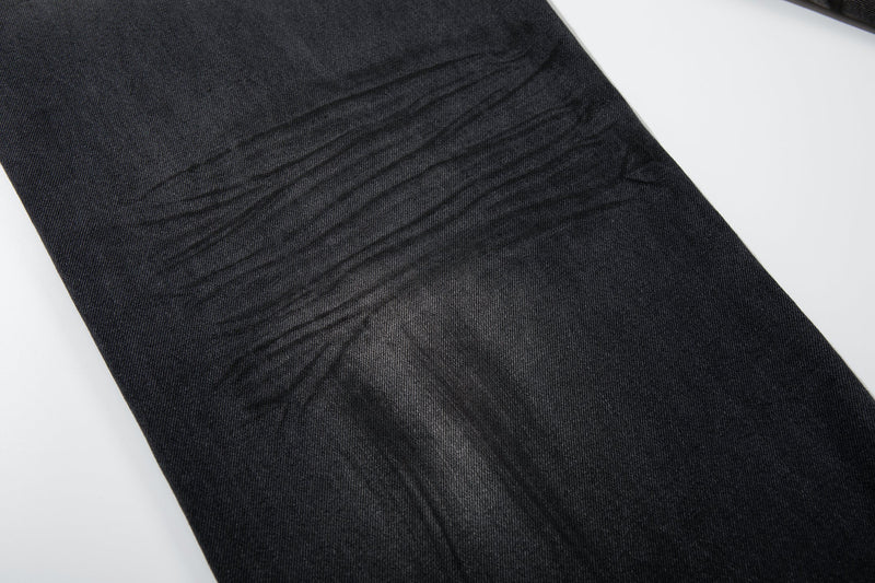 Close-up of dark denim leg with horizontal distressed fade lines and soft worn texture