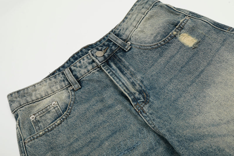 Close-up of front waistband on faded blue jeans with button closure, belt loops, and distressed pocket