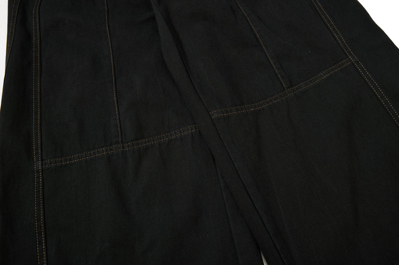 Close-up of black pant leg with seam lines and smooth cotton twill texture