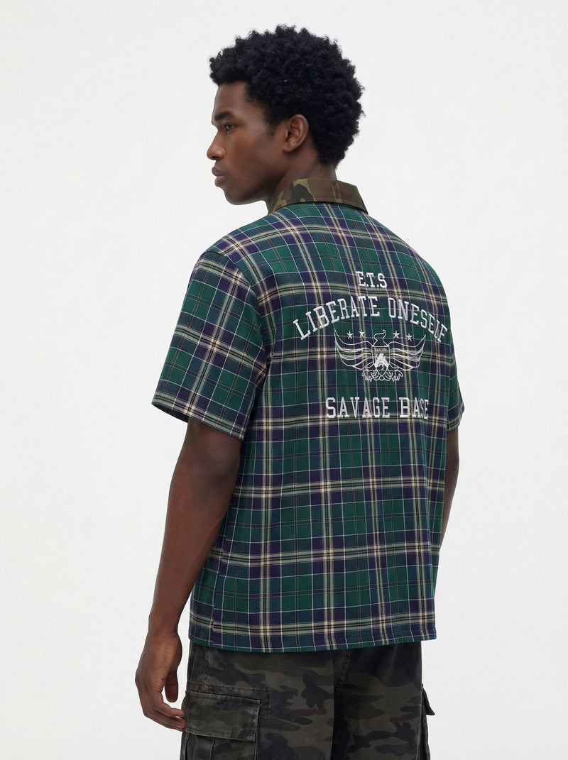 Back view of a green and navy plaid shirt with camouflage collar and bold Savage Base graphic print