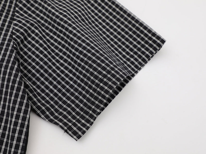 Black and white plaid button-up shirt sleeve with a subtle checked pattern on a clean white background