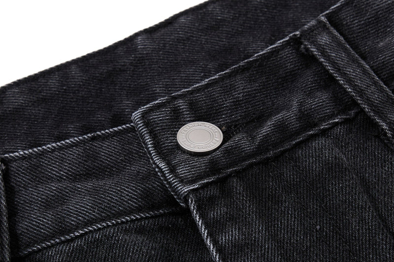 Close-up of black denim waistband and silver button with stitched seam