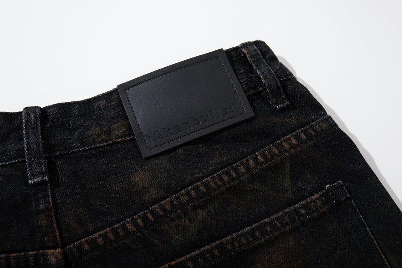Close-up of the waistband, belt loops, and leather logo patch on dark jeans