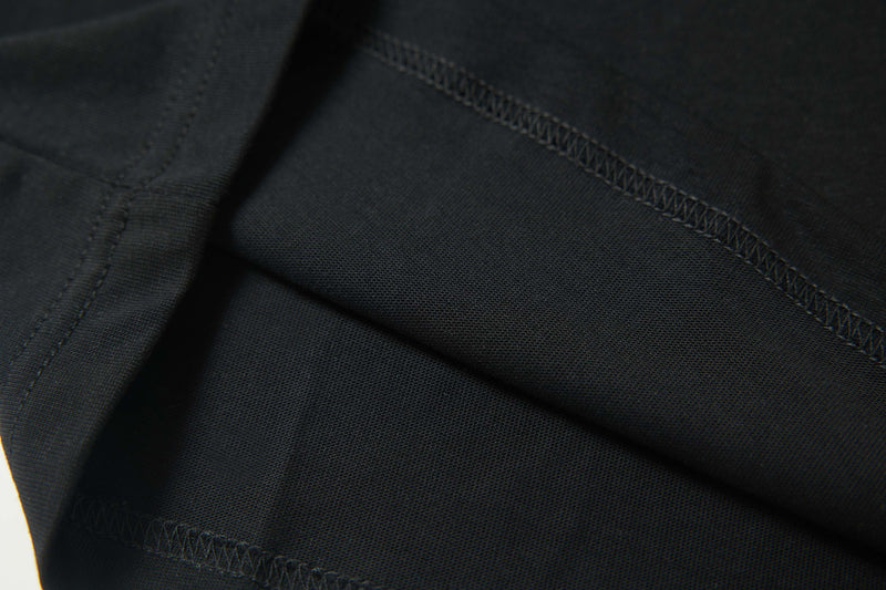 Close-up of black cotton tee fabric with visible stitching and textured streetwear style finish
