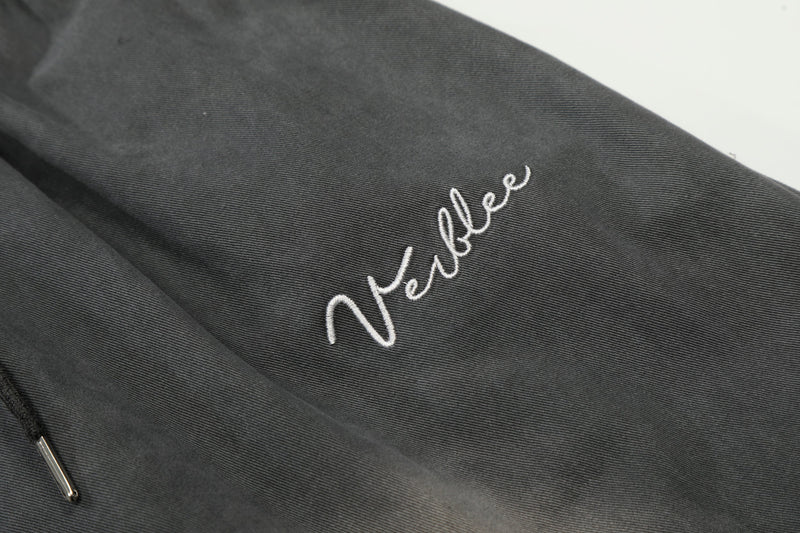 Close-up of white script embroidery on dark gray washed pants
