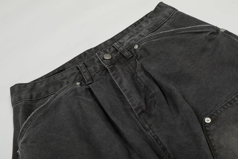 Close-up of the waistband on washed black cargo denim pants with button and belt loops