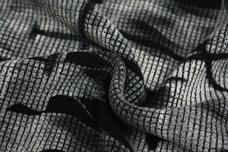 Close-up of black-and-white textured fabric with a skeletal graphic pattern on an oversized cyber-grunge tee