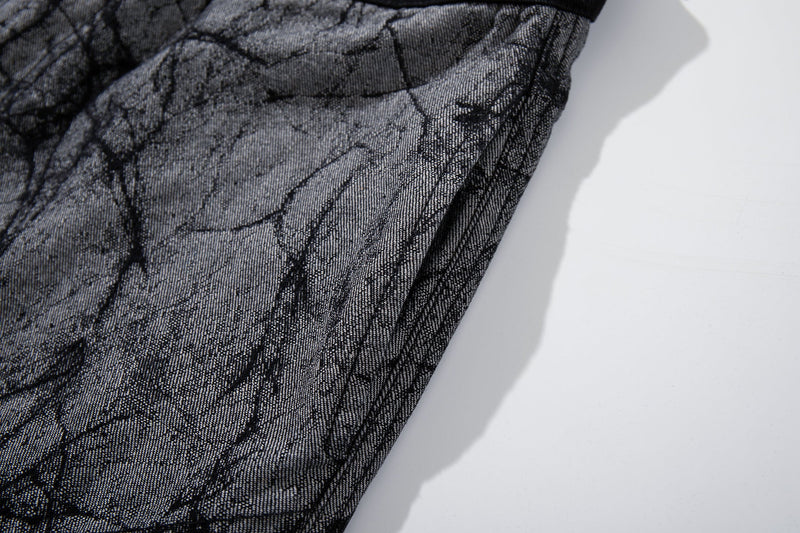 Close-up of gray denim leg with cracked print and stitched side seam