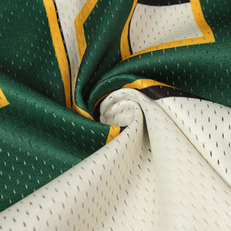 Close-up of green and white mesh football jersey fabric with yellow trim and printed star graphic detailing