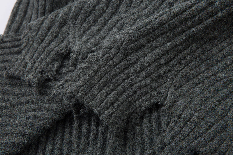 Close-up of charcoal gray distressed knit sleeve and hem folds