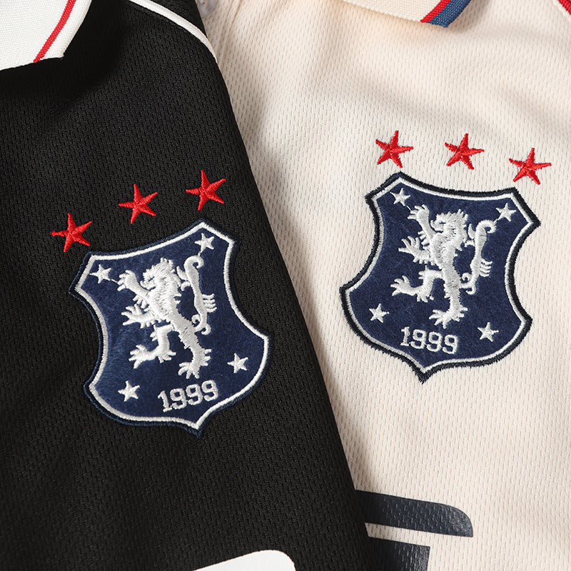 Close-up of black and cream football polo jerseys with embroidered club crest, red stars, and striped collar detail