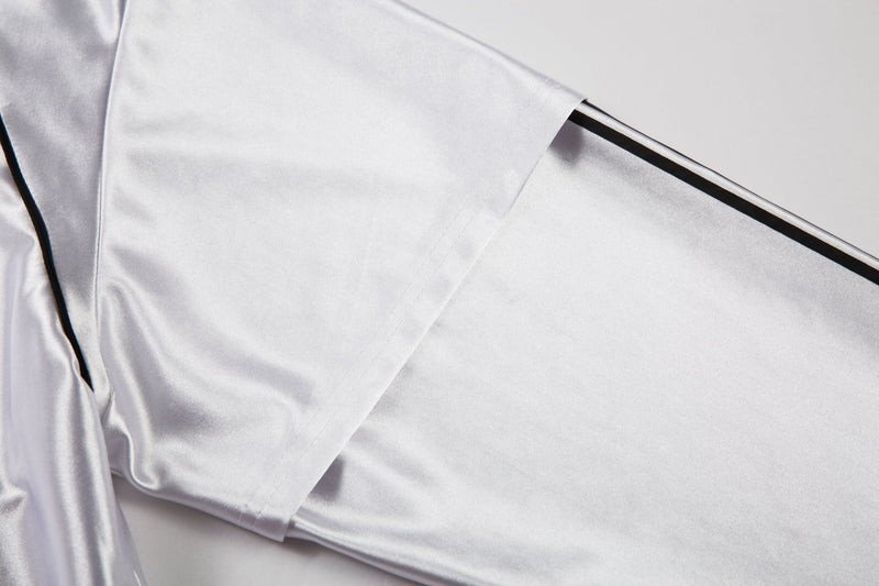 Close-up of white jersey sleeve and shoulder seam with black piping