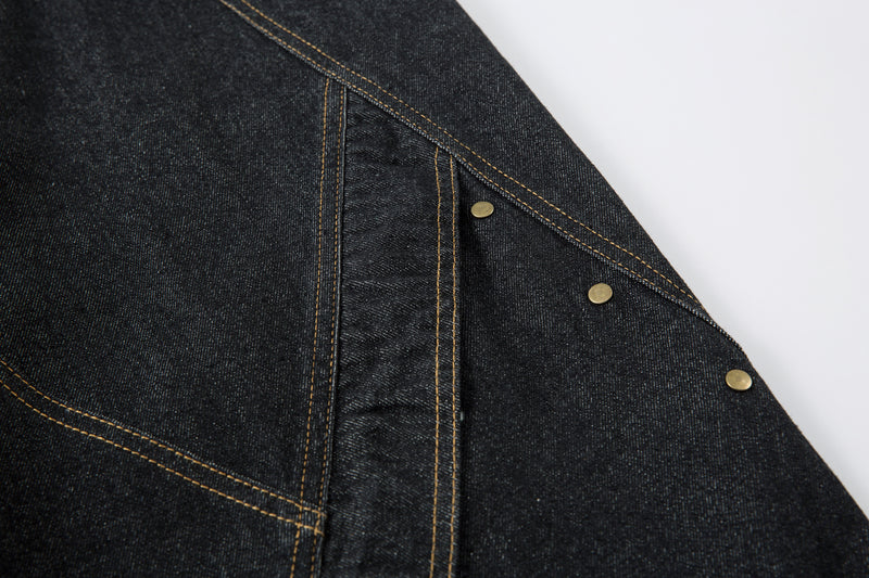 Close-up of side seam and rivet detail on dark denim pants