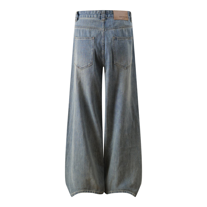 Back view of faded blue wide-leg jeans with patch back pockets and tan leather label