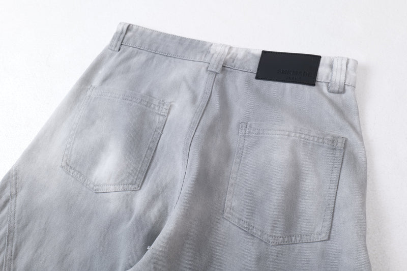 Close-up of the back waistband and pockets on light gray denim jeans with black logo patch