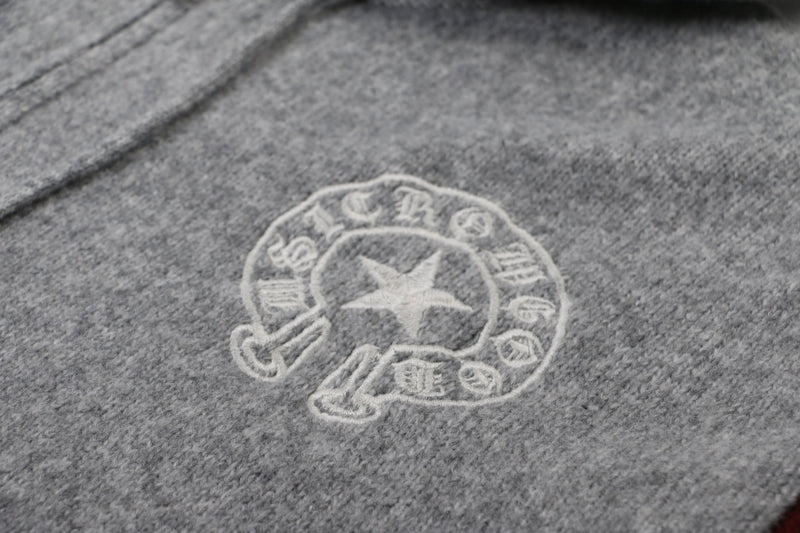Close-up of white embroidered chest emblem on gray knit hoodie