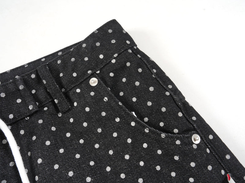 Close-up of black polka-dot denim waistband and front pocket area with snap button