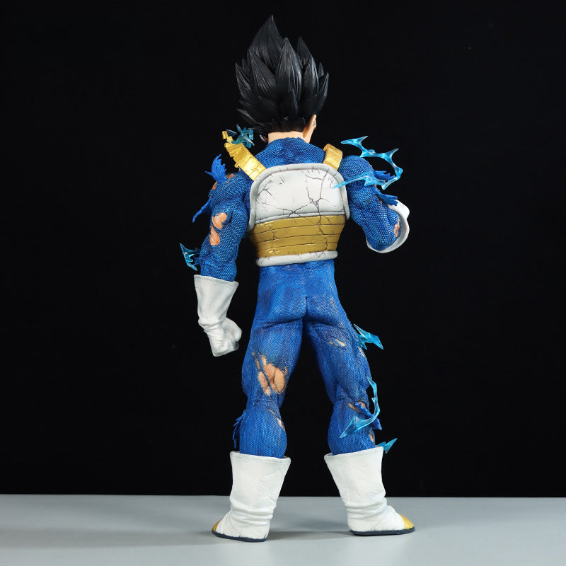 The Seakoff Vegeta Collectible Figure (45cm) from Dragon Ball Z features Vegeta in a blue and gold battle suit with tattered clothing and iconic spiky black hair, standing back to the viewer against a black backdrop. Includes 4 interchangeable heads showcasing Super Saiyan forms.