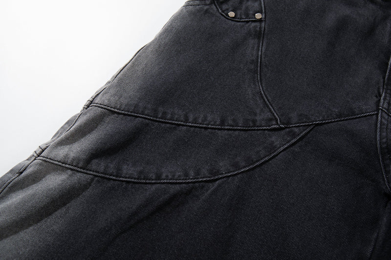 Close-up of the side seam and curved panel stitching on washed black denim