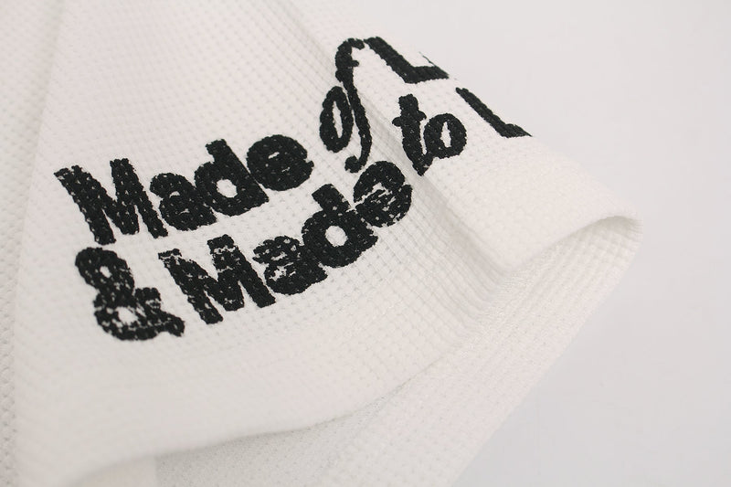 Close-up of white streetwear tee with distressed black Made of Love graphic and heart print on textured fabric