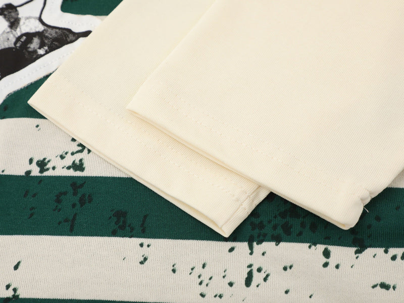 Close-up of cream tee sleeve laid over green striped body with patch detail
