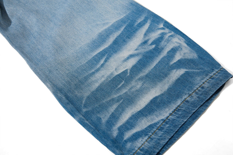 Close-up of faded denim leg with heavy wash pattern and hem stitching