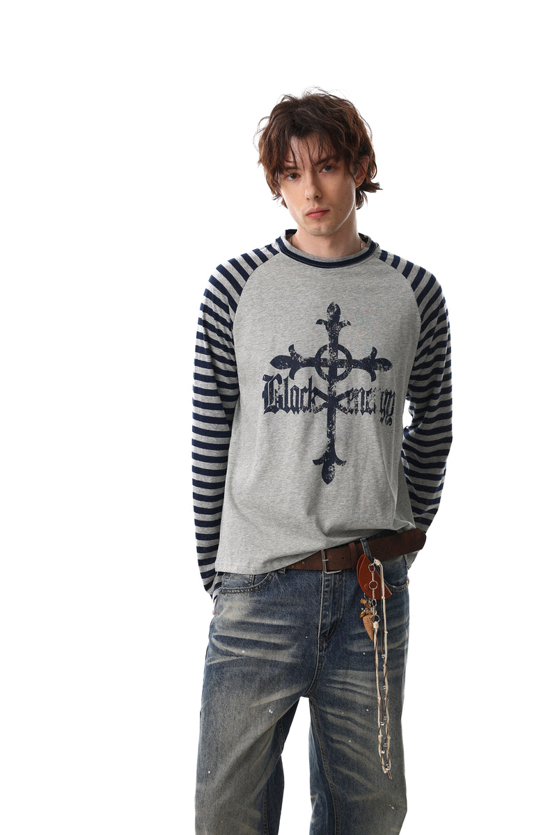 Model wearing gray raglan long sleeve tee with navy striped sleeves and gothic cross graphic