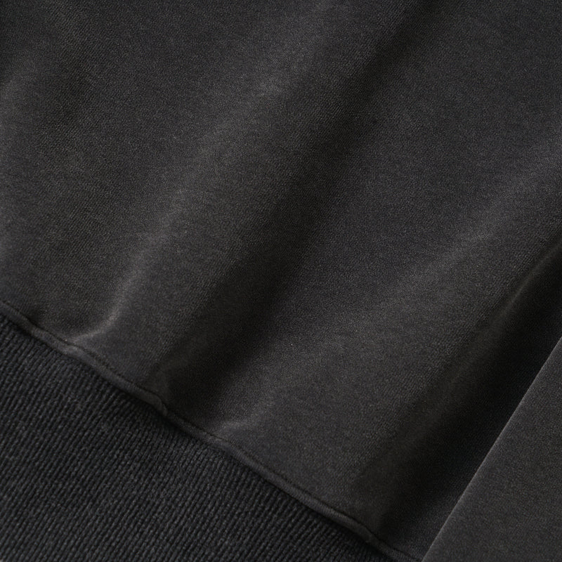 Close-up of smooth black hoodie fabric with ribbed hem edge