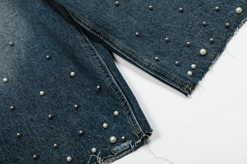 Close-up of wide-leg denim hem with pearl studs and frayed edge