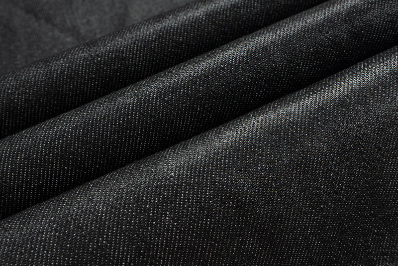 Close-up of black coated denim fabric texture with soft folds
