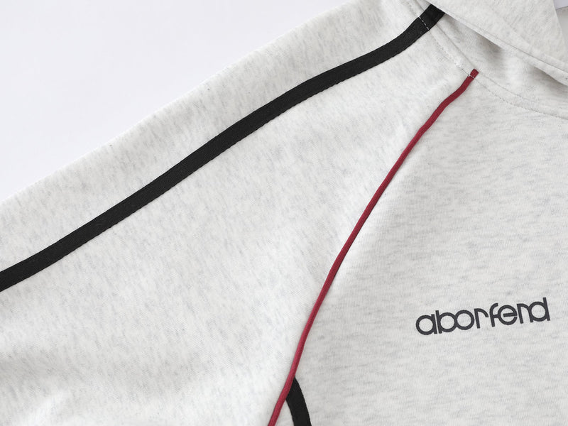 Close-up of light gray hoodie shoulder and chest with black stripe, red piping, and logo