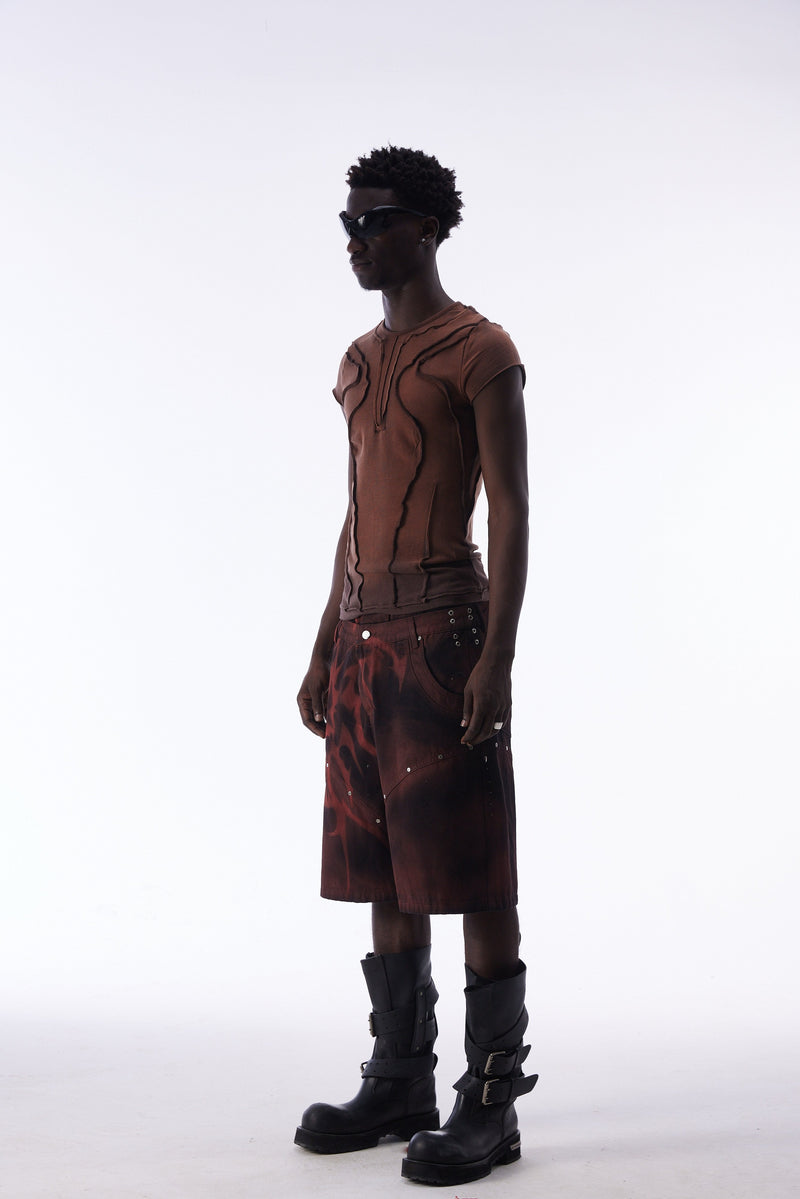 Side view of model wearing burgundy and black jorts with tribal print and boots