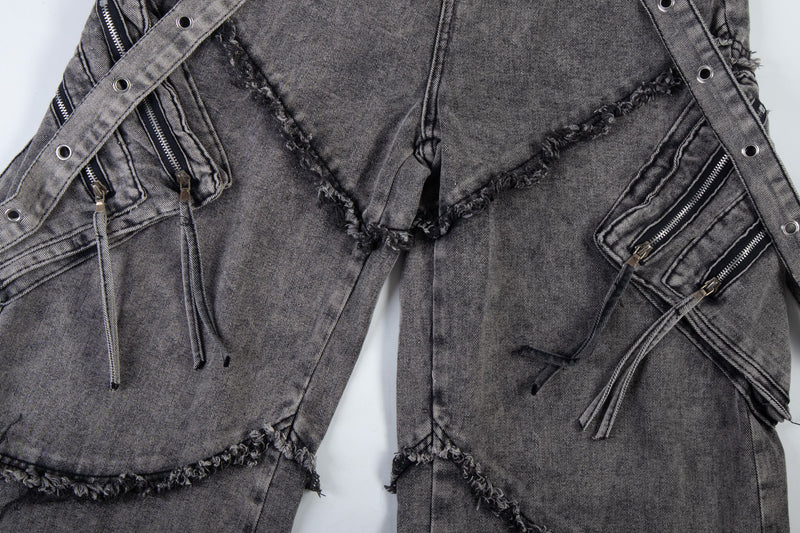 Front upper section of washed black cargo jeans with frayed seam panels and side zippers